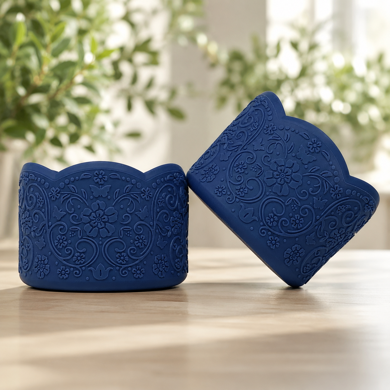 Abbie navy blue silicone tumbler boots, a pair on a wood table showing the vintage floral embossing and scalloped edge.