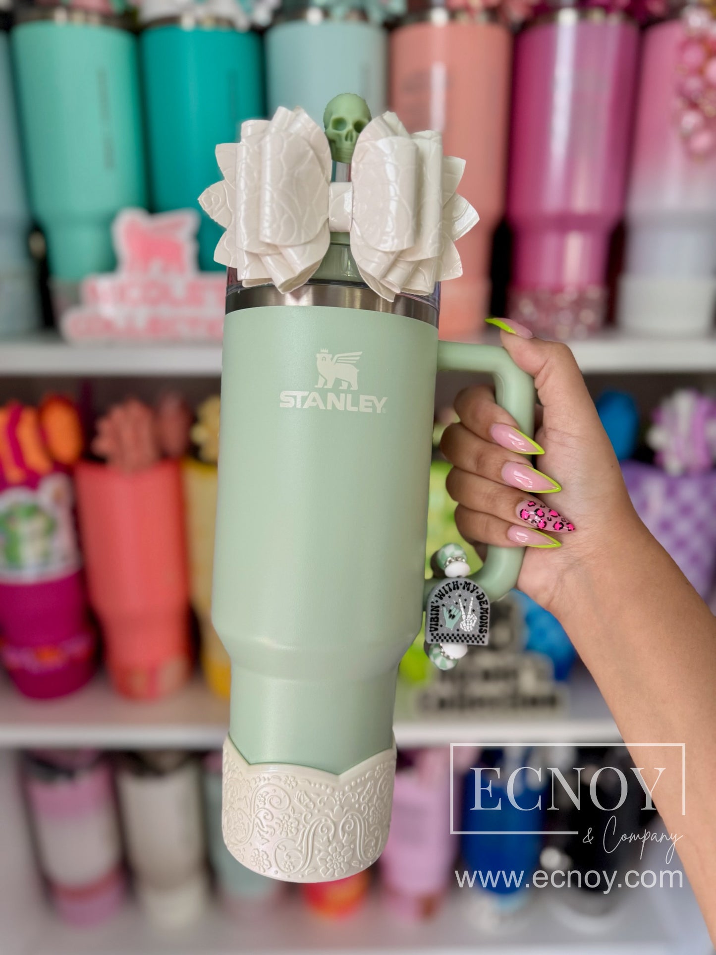 Aalijah Shimmer boot from the Ecnoy LUXE Collection — cream shimmer finish, scalloped edge, vintage-inspired floral embossed pattern — pictured on a Stanley Quencher 40oz Traveler tumbler in Pistachio (green).