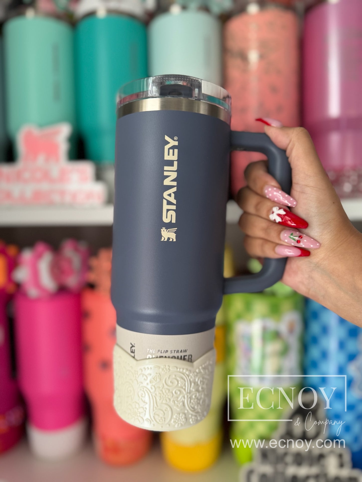 Aalijah Shimmer boot from the Ecnoy LUXE Collection — cream shimmer finish, scalloped edge, vintage-inspired floral embossed pattern — pictured on a Stanley Quencher ProTour Flip Straw 40oz tumbler in Blue.