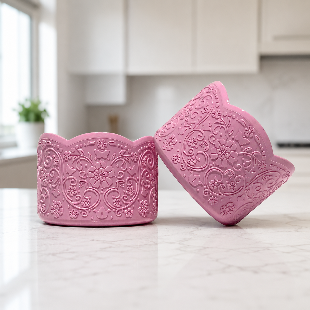 Maeve Gloss LUXE Collection silicone tumbler boot in glossy pink tulle by Ecnoy & Company, scalloped floral-embossed design shown as two boots on a marble kitchen counter.