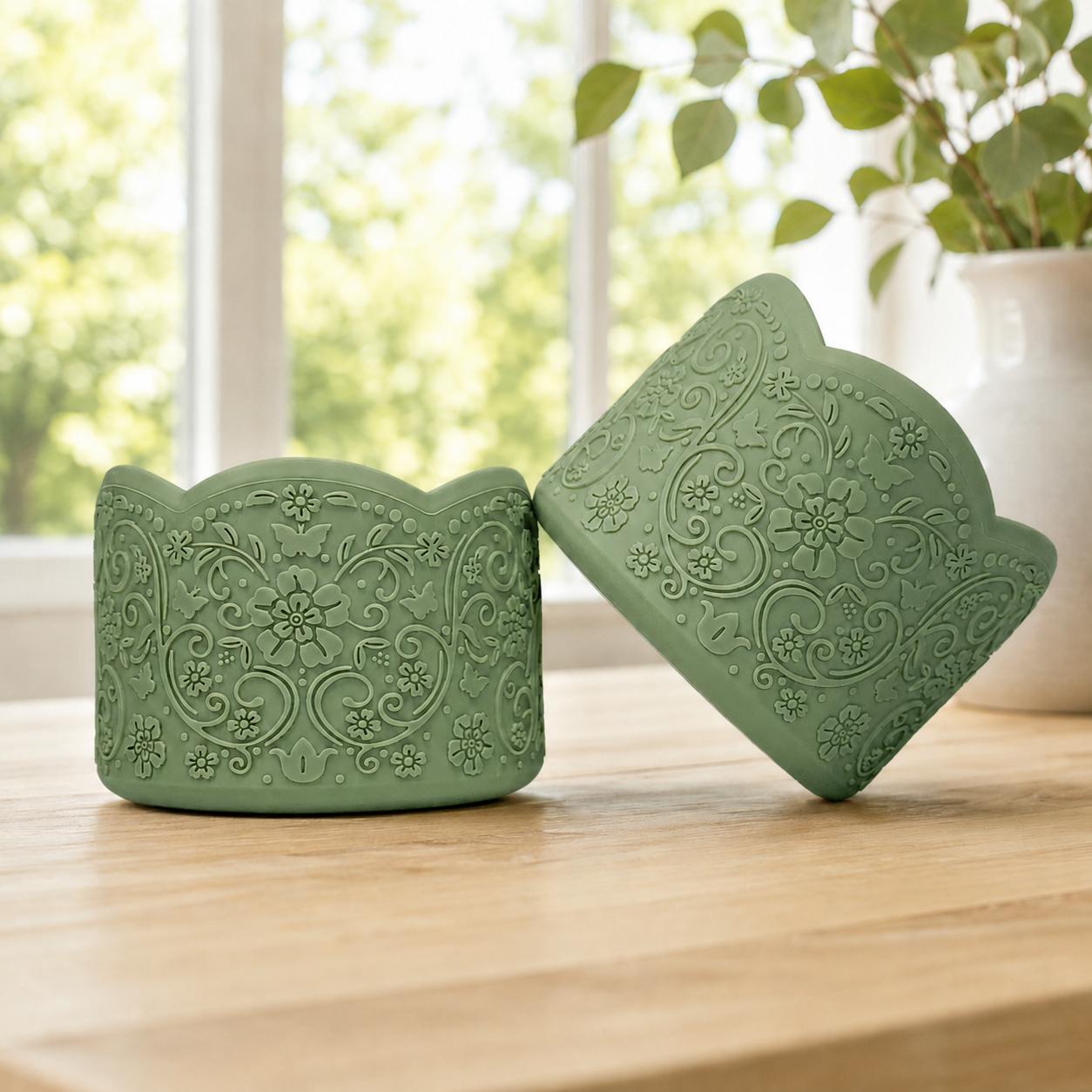 Samah leafy green silicone tumbler boots, a pair on a wood table showing the vintage floral embossing and scalloped edge.